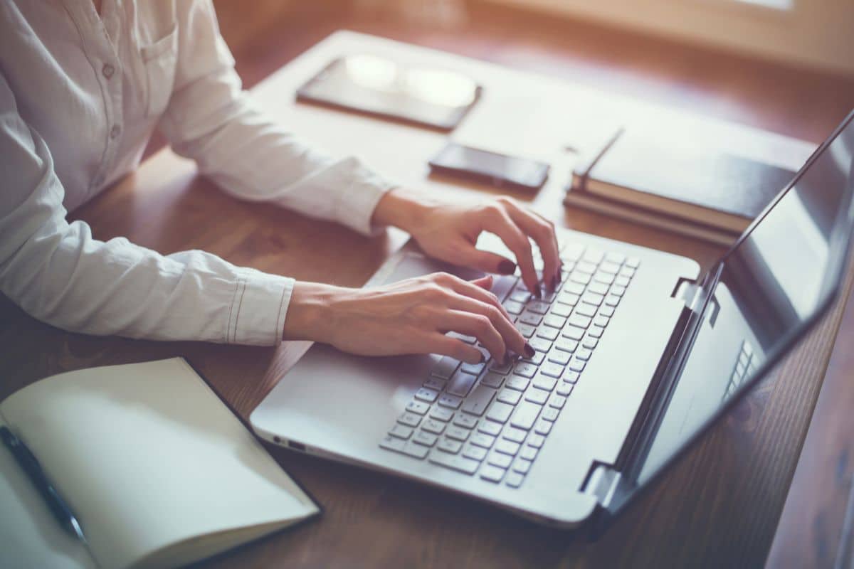 femme qui tape sur les touches d'un ordinateur. Cette image illustre l'article "Les bases du copywriting : techniques et conseils pratiques"